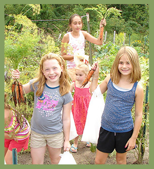 Students hold carrots pulled from a garden