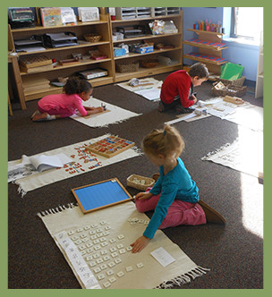 Three students sit on the floor and work on projects