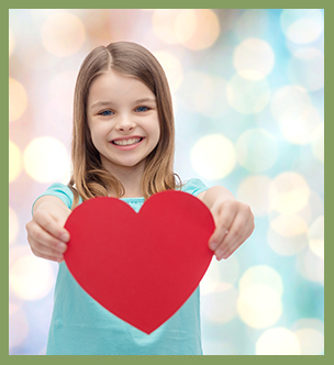 Happy school girl holding up a red paper heart